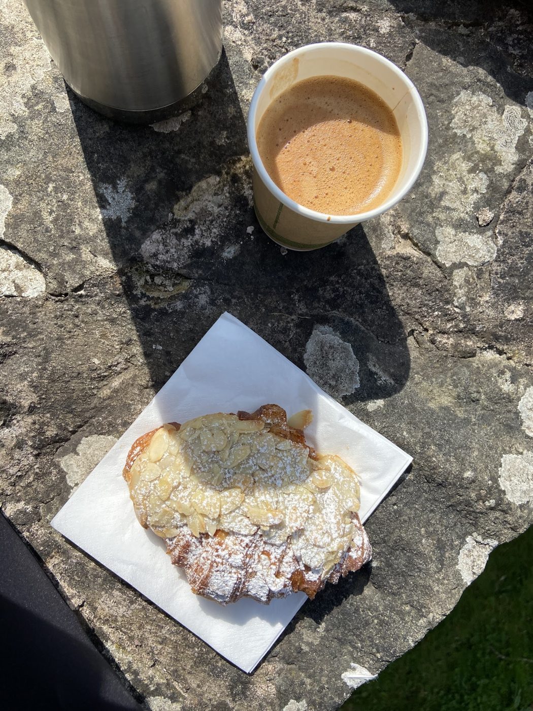 A takeaway coffee and a pastry on a paper napkin