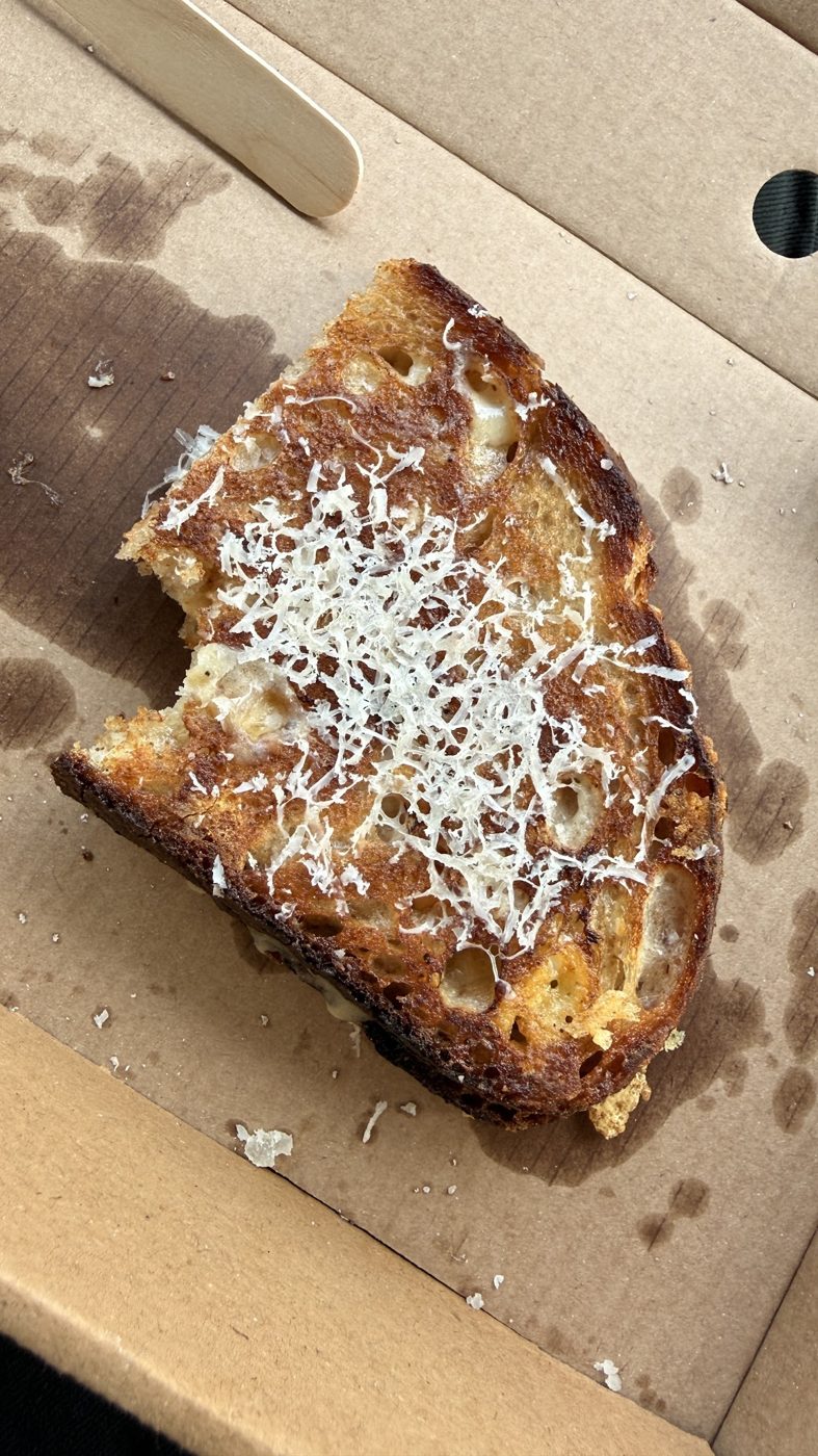 A cheese toastie with grated cheese in a takeaway box